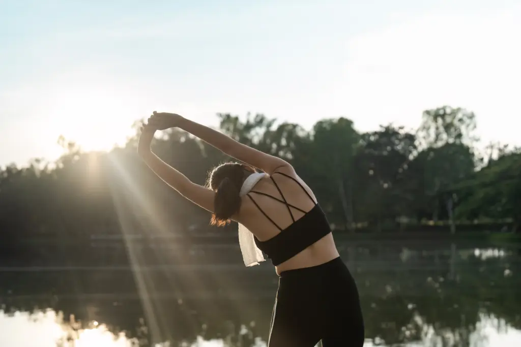 A runner stretching beside a lake