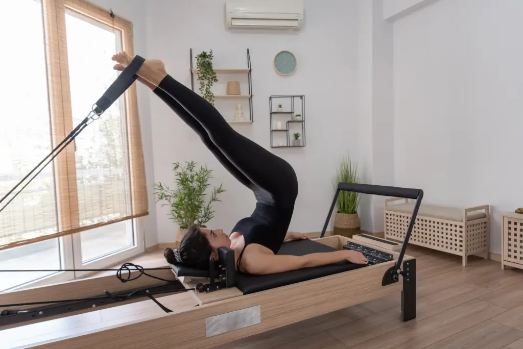 A student exercising on a Pilates reformer